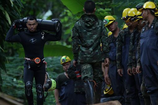 A diver carries an oxygen tank as he leaves the Tham Luang cave complex, where 12 boys and their soc