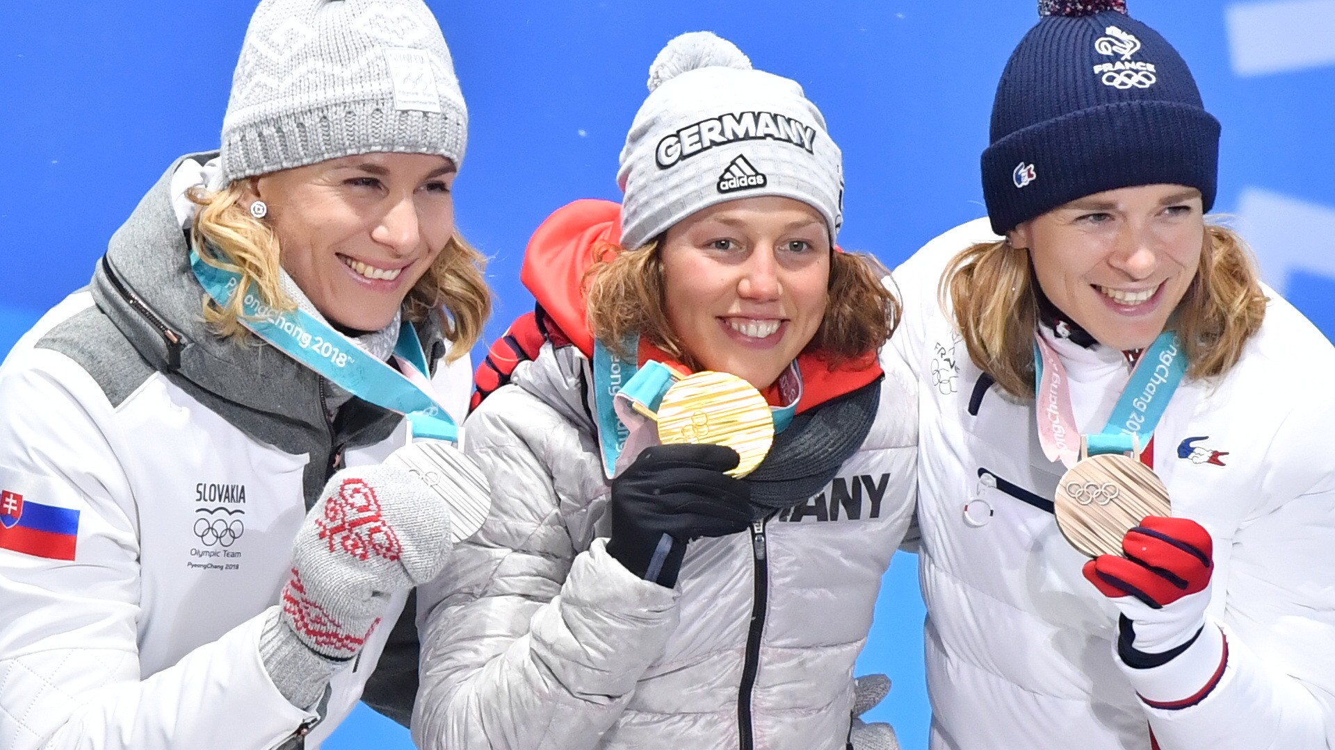 Slovenská biatlonistka Anastasia Kuzminová pózuje so striebornou medailou, ktorú získala na ZOH 2018, uprostred Nemka Laura Dahlmeierová.