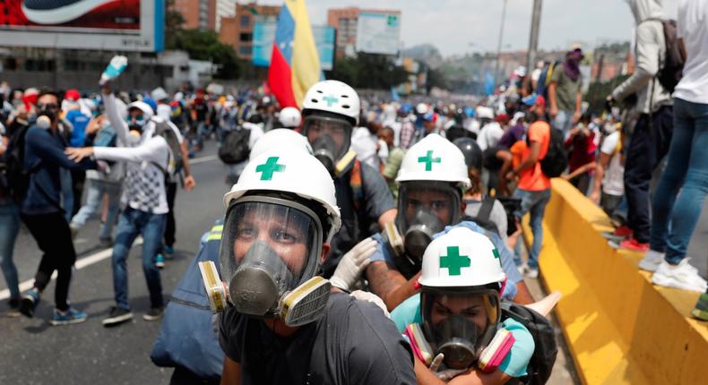 Volunteers, members of a primary care response team, huddle together during clashes with security forces at a rally against Venezuela's President Nicolas Maduro in Caracas, Venezuela.