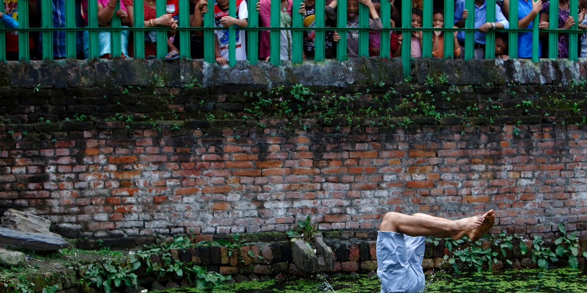 A devotee dives into a pond during the Deopokhari festival in Khokana