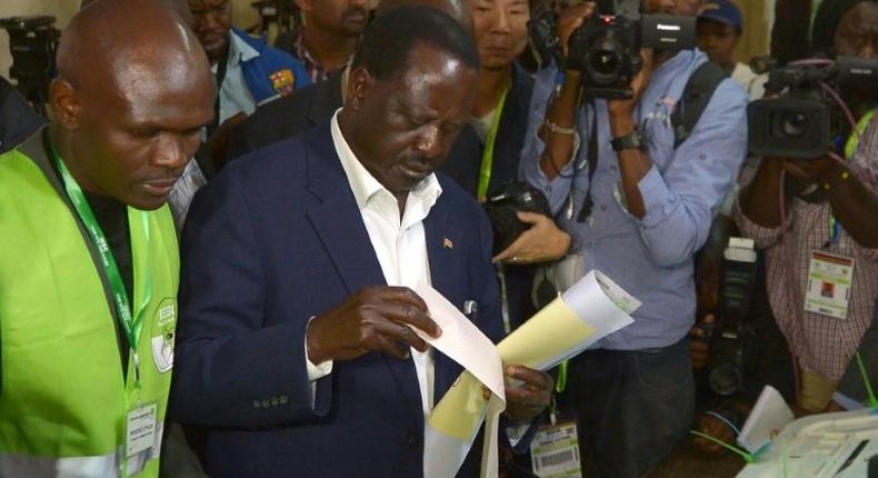 Kenya's opposition alliance, National Super Alliance (NASA) presidential candidate, Raila Odinga prepares to cast his ballots on August 8, 2017 mobbed by a battery of photo journalists at Old-Kibera primary school polling centre, in Nairobi