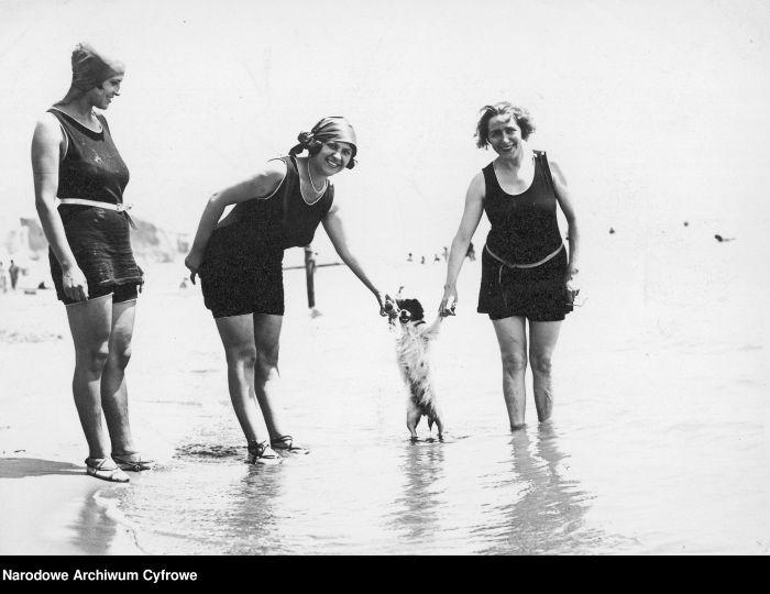 Kobiety w kostiumach kąpielowych pozują z psem na plaży, 1918 r.