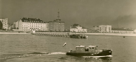 Rok 1933 r. widok na budynki stojące przy ul. Waszyngtona (do 1933 r. ul. Nadbrzeżna). Wzdłuż plaży ciągnie się ulica Waszyngtona. Na niej, od lewej strony, zabudowany w 1929 roku, budynek biurowy Żeglugi Polskiej (obecnie gmach Dowództwa Floty). W tym samym roku zbudowano stojący obok gmach Państwowego Instytutu Meteorologicznego; konstrukcję stalowej wieży zamontowano na budynku w 1930 r. Dalej budynek Biura Budowy Portu, w którym od 1930 r., mieszkał inż. Tadeusz Wenda..