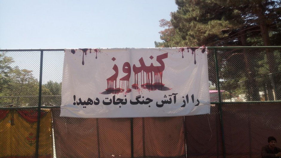 Plakat z napisem Kunduz (Save it from the fire of war), umieszczony przy miejscu koczowania przesiedlonych ludzi