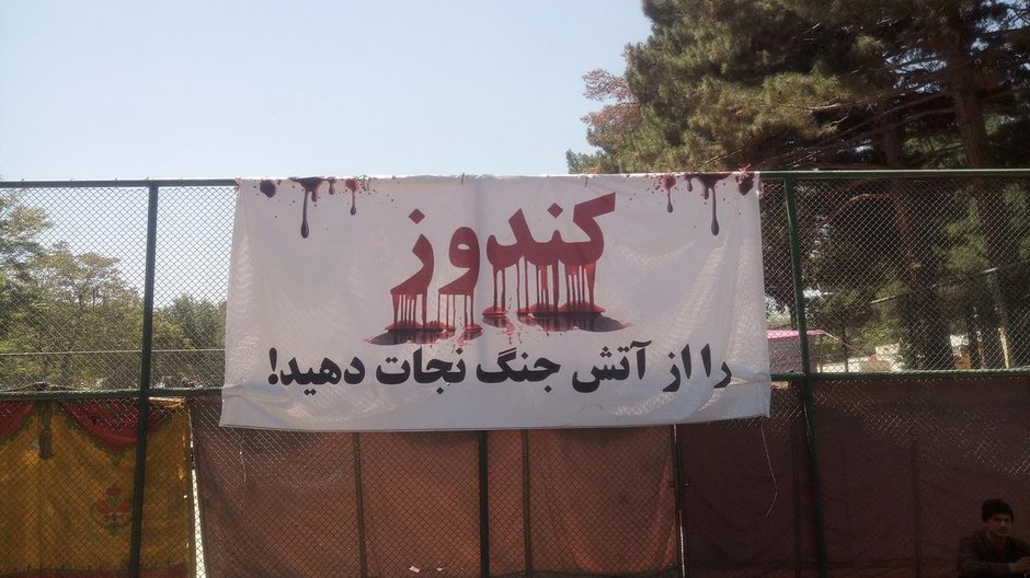 Plakat z napisem Kunduz (Save it from the fire of war), umieszczony przy miejscu koczowania przesiedlonych ludzi