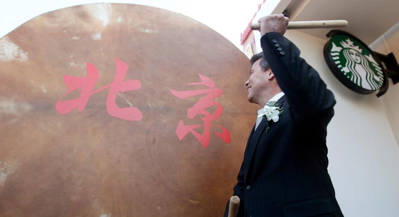 Starbucks Coffee International President John Culver beats a drum during the official unveiling ceremony of the new Starbucks logo at the Solana store in Beijing.