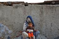 A woman rests with her child while working as a day labourer in Delhi