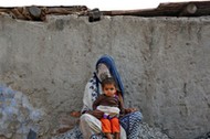 A woman rests with her child while working as a day labourer in Delhi