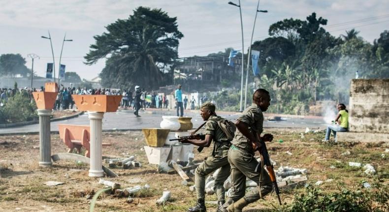 Gabonese soldiers run to take position as supporters of opposition leader Jean Ping protest in front of security forces blocking a demonstration trying to reach the electoral commission in Libreville