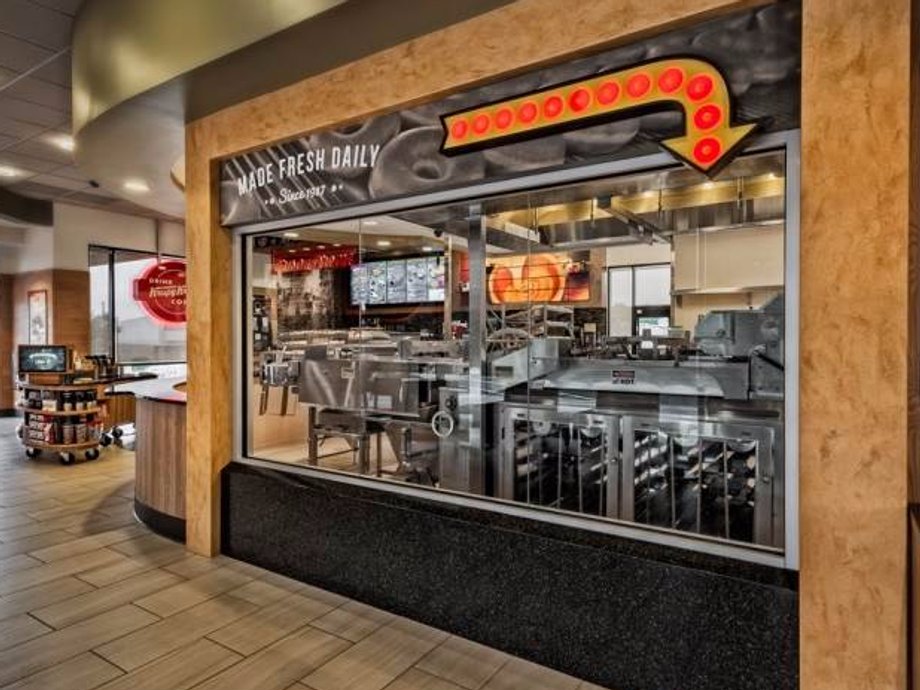 The new location keeps the iconic window through which Krispy Kreme customers can see the glaze waterfall at work.