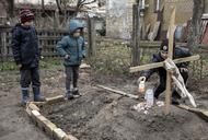 Wojna w Ukrainie. Dzieci na grobie matki zabitej w Buczy i pochowanej na podwórku domu