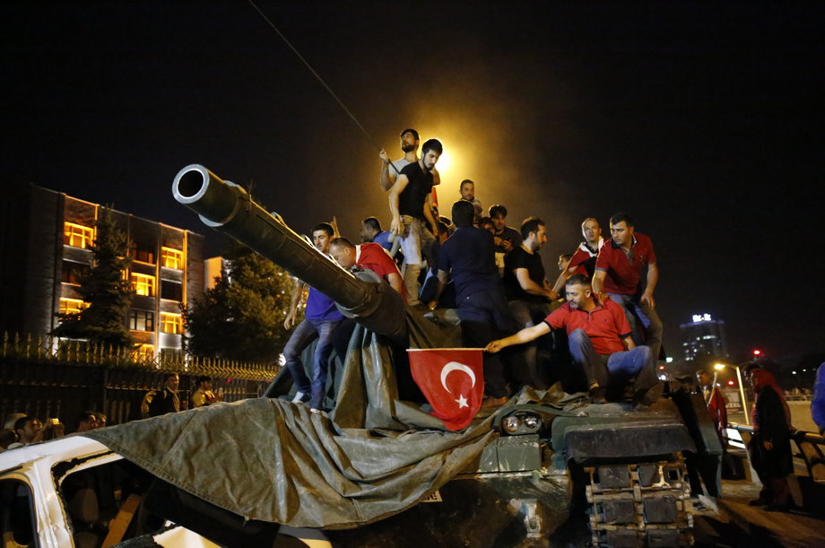 People stand on a Turkish army tank in Ankara, Turkey, July 16, 2016.