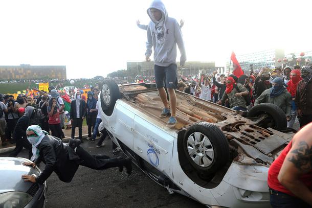 Anti-government demonstrators gesture atop a press car of Tv Record as they attend a demonstration a