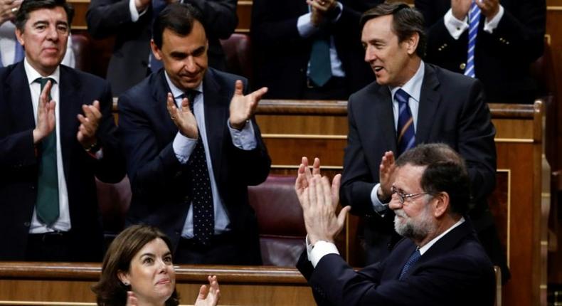 Spaain's Prime Minister Mariano Rajoy (R) is applauded by party colleagues at the Congress of Deputies in Madrid on June 14, 2017 after his party survived a vote of no confidence tabled to denounce a series of corruption scandals