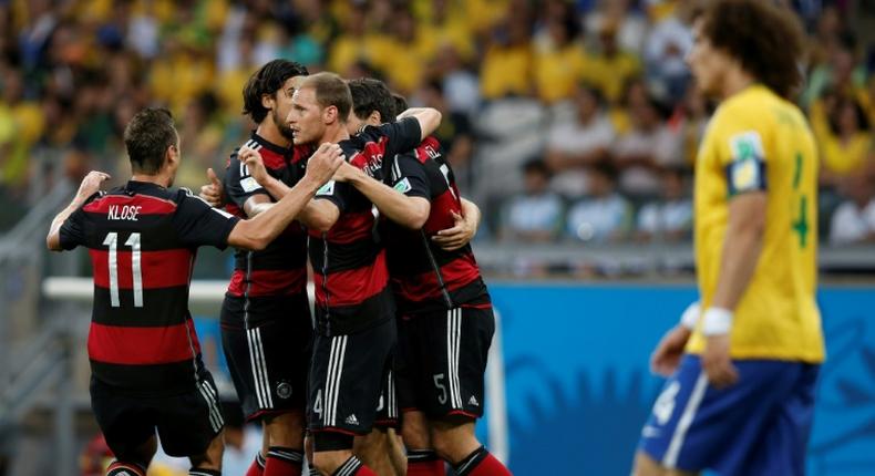 Germany players celebrate after Thomas Mueller opens the scoring against Brazil as a forlorn David Luiz looks on disconsolately