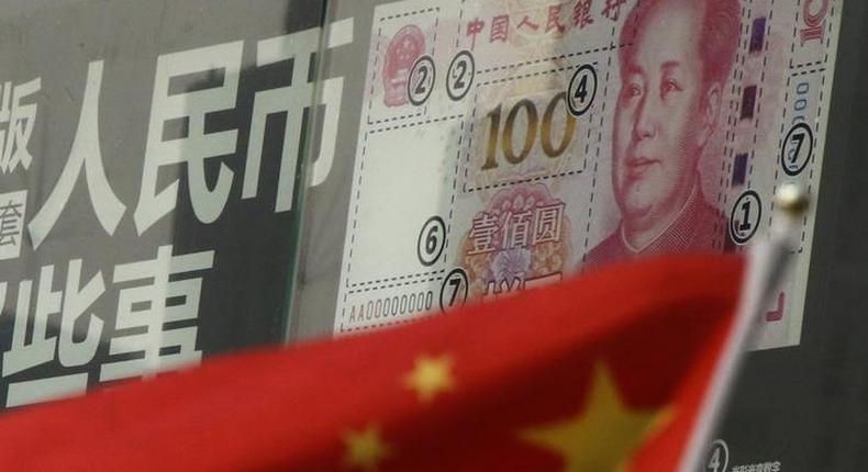 China's national flag is seen in front of a poster explaining the design of new 100 yuan banknote at a branch of a commercial bank at a business district in Beijing, China, January 21, 2016. 