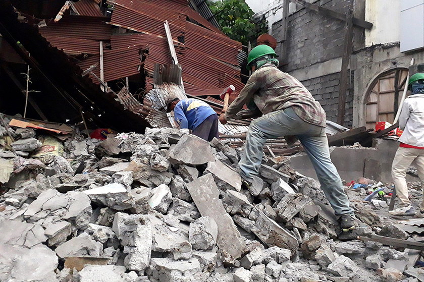 Workers clear concrete debris as they search for possible casualties at the ruins of an old building