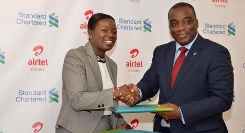 Managing Director of Airtel Ghana  Lucy Quist exchanging files with CEO of Standard Chartered Bank  Mr. Kweku Bedu-Addo