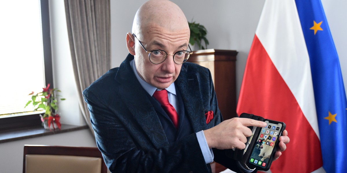 Wicemarszałek Senatu Michał Kamiński pilnuje swojego telefonu.