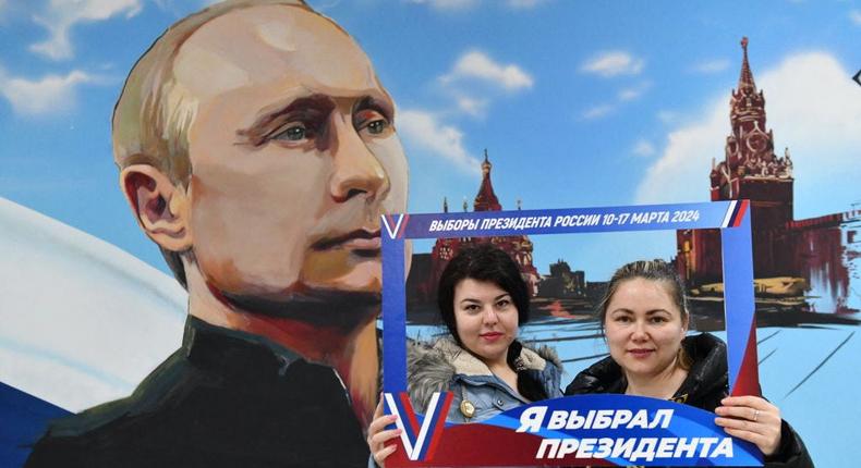 Women posing in front of a mural of Russian President Vladimir Putin after voting in Russia's presidential election at a polling station in Donetsk, Russian-controlled Ukraine, on Friday.AFP/Getty Images