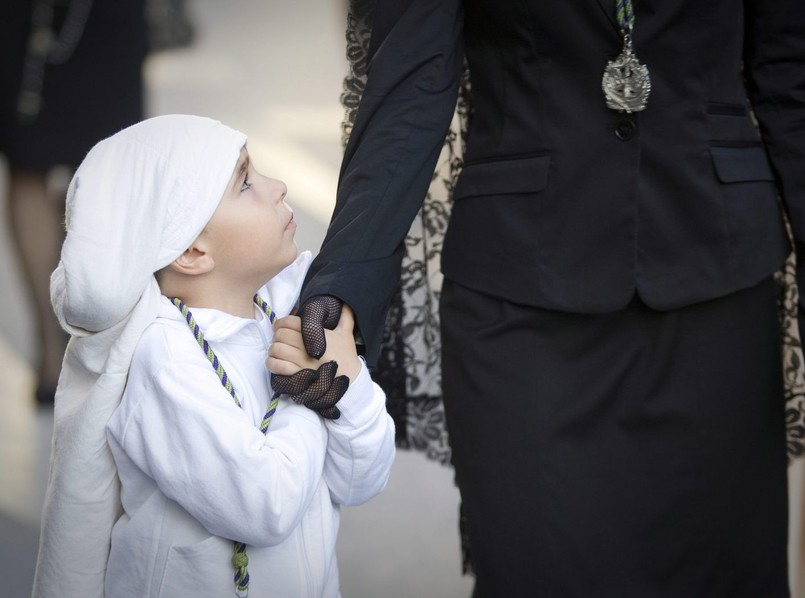 Chłopiec ubrany w strój członka bractwa religijnego idzie na procesję w Almerii