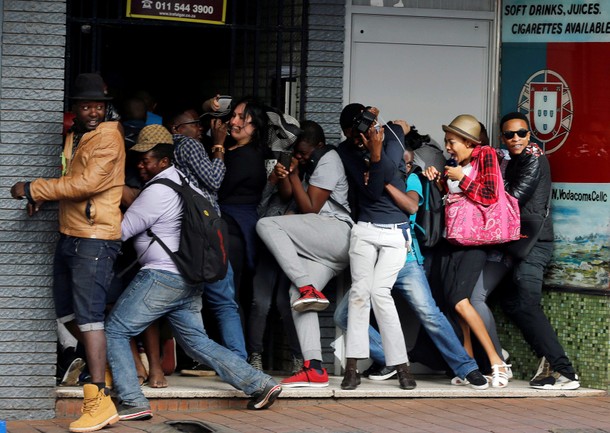 Students demanding free education react as they are fired at by riot police officers during a protes