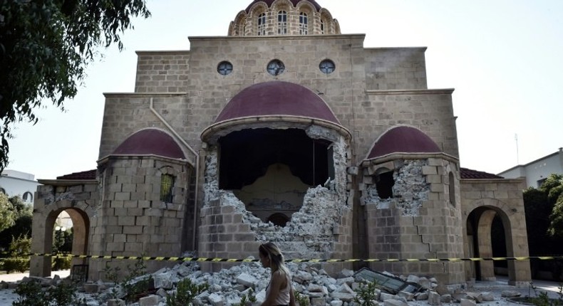 A woman walks past a damaged church on the Greek island of Kos following a 6.7 magnitude earthquake which struck the region on July 21, 2017