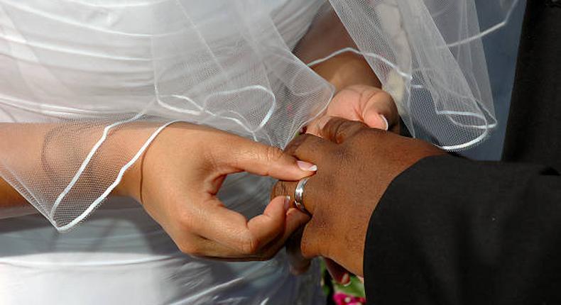 A bride inserting a ring on her grooms finger