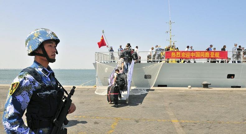 A navy soldier (L) of People's Liberation Army (PLA) stands guard as Chinese citizens board the naval ship Linyi at a port in Aden, in this March 29, 2015 file photo. REUTERS/Stringer/Files
