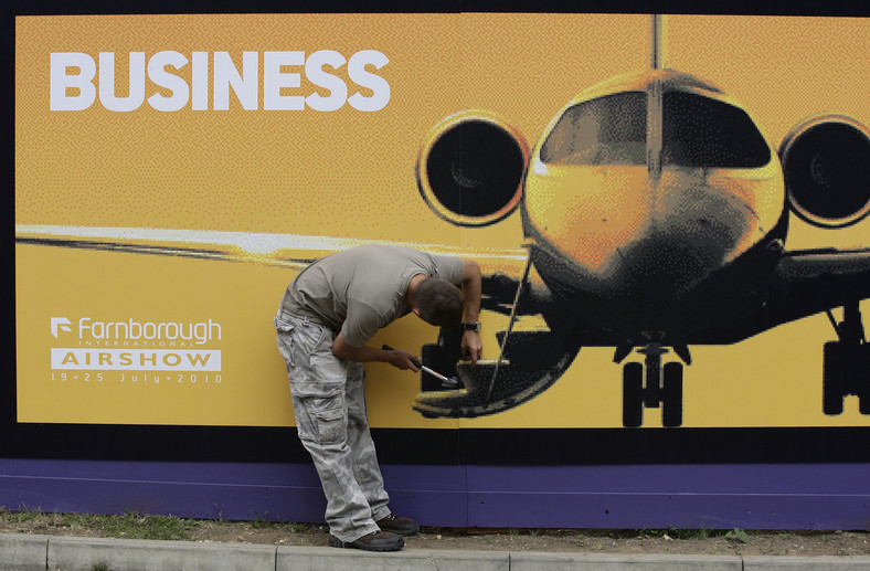 Jeden z pracowników Farnborough International Airshow montuje znak witający gości, fot. Simon Dawson/Bloomberg