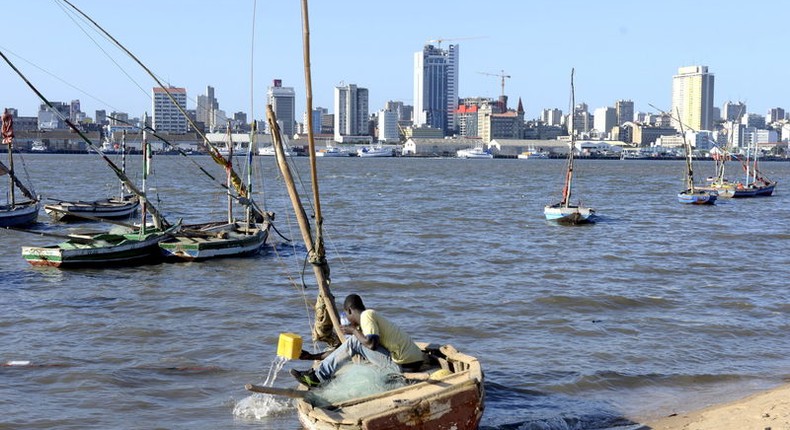 A fisherman cleans his boat beneath Maputo's skyline, Mozambique, August 15, 2015. 