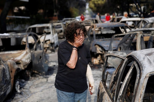 A woman reacts as she tries to find her dog, following a wildfire at the village of Mati, near Athen