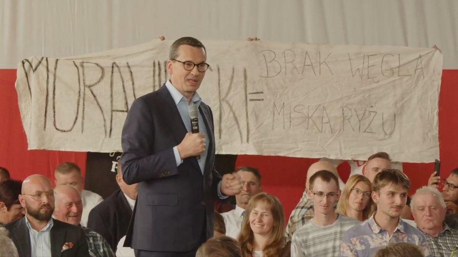 Mateusz Morawiecki w Żalnie. Za nim transparent "Morawiecki = brak węgla i miska ryżu" (03.09.2022)