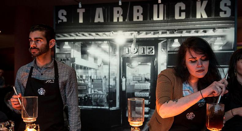 Starbucks workers preparing coffee using the siphoning technique, which is available at stores with Reserve Bars.