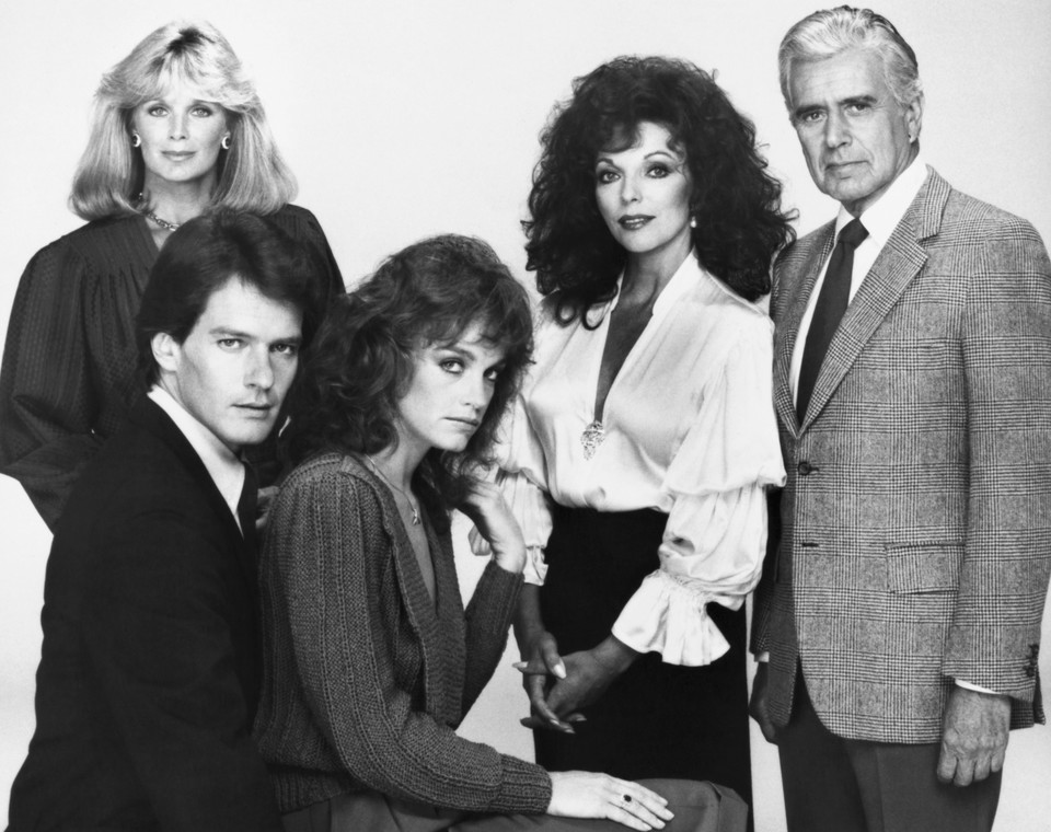 Gordon Thomson jako Adam Alexander Carrington (1982-1989). Na zdjęciu pierwszy z lewej na dole; poza tym widzimy Lindę Evans, Pamelę Sue Martin, Joan Collins i Johna Forsythe