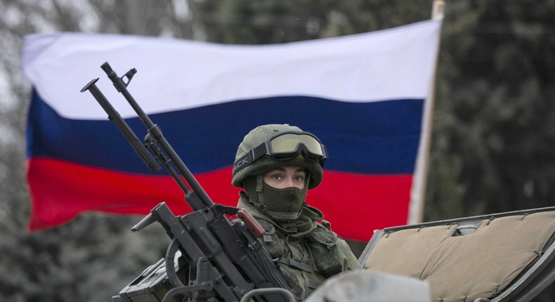 A pro-Russian man (not seen) holds a Russian flag behind an armed servicemen on top of a Russian army vehicle outside a Ukrainian border guard post in the Crimean town of Balaclava March 1, 2014.Baz Ratner/Reuters