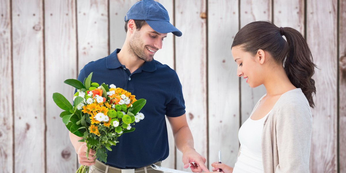 Happy flower delivery man with customer against wooden planks