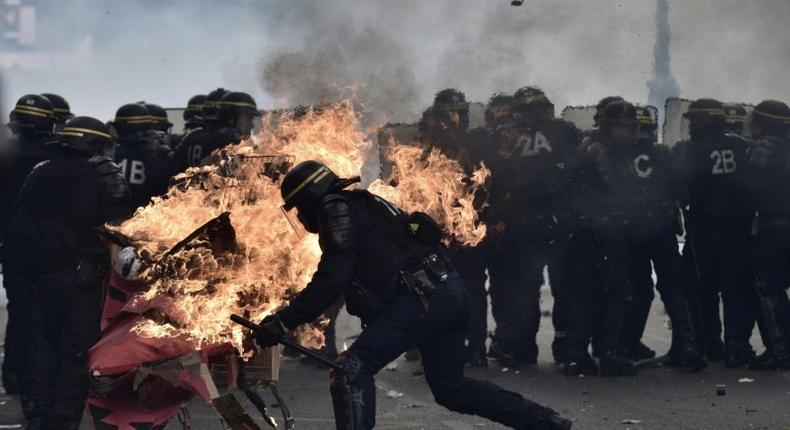 French anti-riot police try to push away a burning trolley launched towards them at a May Day rally in Paris