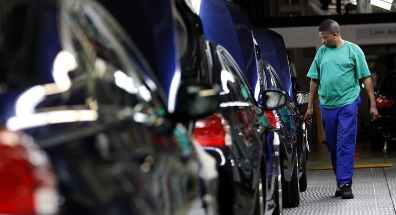 A worker walks near a row of cars at BMW's manufacturing plant in Rosslyn, outside Pretoria, September 13, 2010. REUTERS/Siphiwe Sibeko