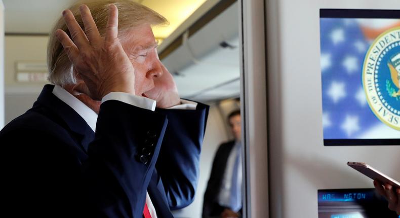 President Donald Trump reacts as he speaks to reporters aboard Air Force One.