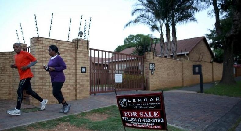 A couple jogs past a for sale sign outside a house in Johannesburg, February 1, 2016. REUTERS/Siphiwe Sibeko