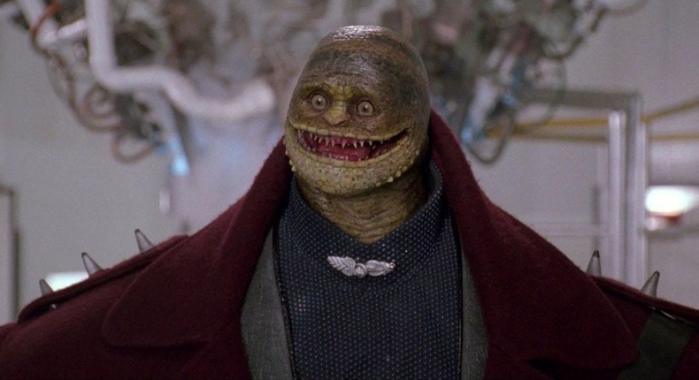 A screenshot from the 1993 Super Mario Bros. movie featuring the film's version of a Goomba villain from the game series.
