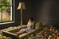 Woman sitting on sofa surrounded by flowers