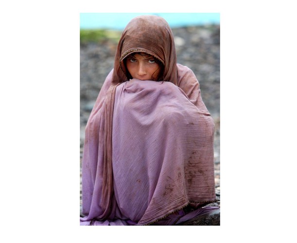 Dziewczynka siedzi w deszczu na zalanych terenach wokół miasta Nowshera w Pakistanie