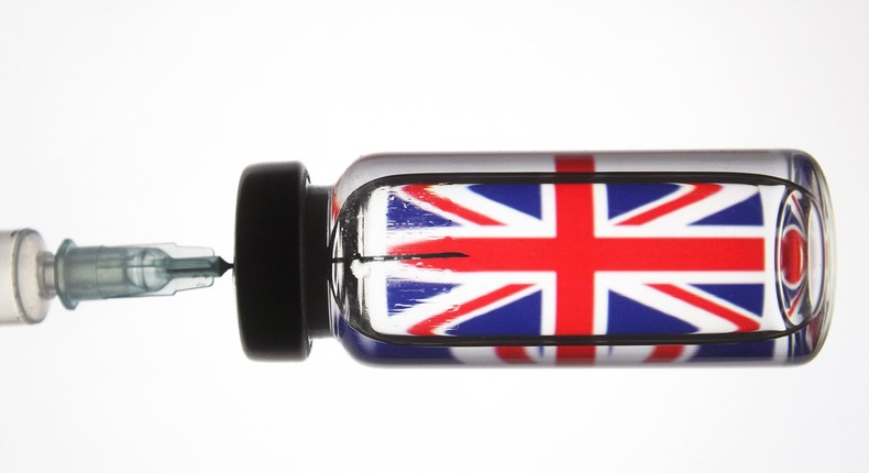 A dummy coronavirus vaccine placed in front of the British flag.