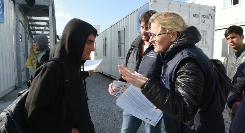 Employees of France's 'Department for Social Cohesion and Protection of the Population' distribute documents to migrants on the Jungle camp's demolition at a reception centre in Calais, northern France, on October 23, 2016