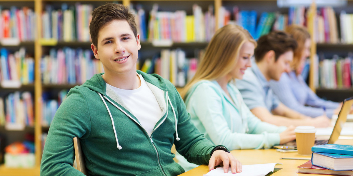 happy student boy reading books in library