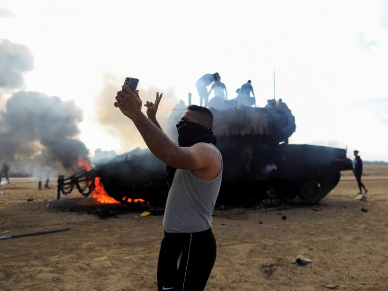 9. A Palestinian man takes a selfie in front of a burning Israeli tanks