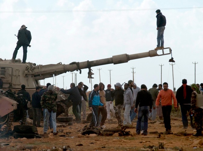 Rebelianci na spalonym czołgu, należącym do sił Muammara Kadafiego, zniszczonym podczas francuskiego nalotu 25 km od Bengazi