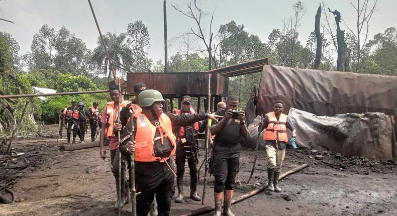 Commander of NNS Pathfinder, Commodore Desmond Igbo, taking newsmen around illegal refinery in Rivers State [NAN]